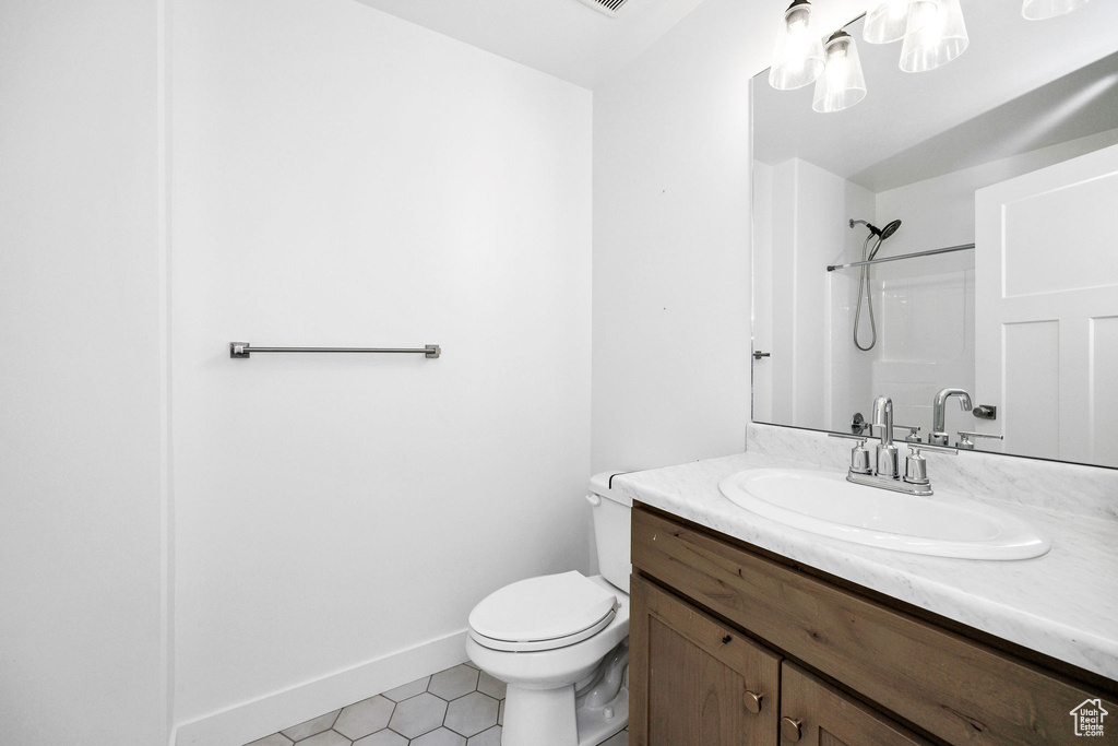 Full bath with vanity, toilet, baseboards, tile patterned floors, and walk in shower