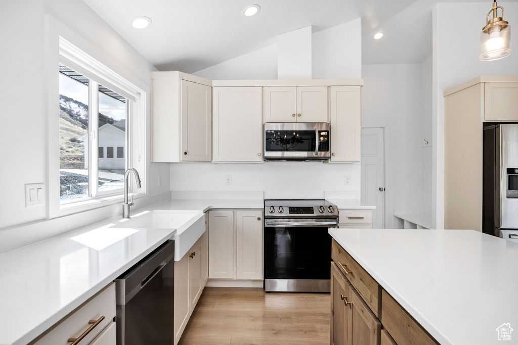 Kitchen featuring light wood finished floors, stainless steel appliances, recessed lighting, a sink, and vaulted ceiling