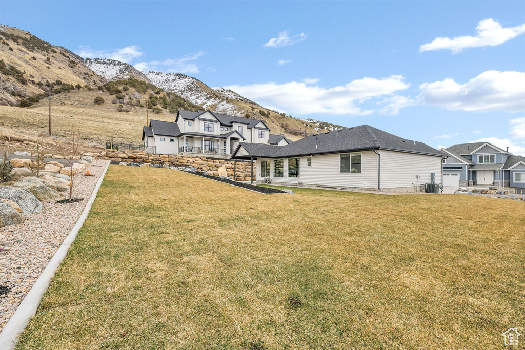 Rear view of house with a lawn, a mountain view, cooling unit, and fence