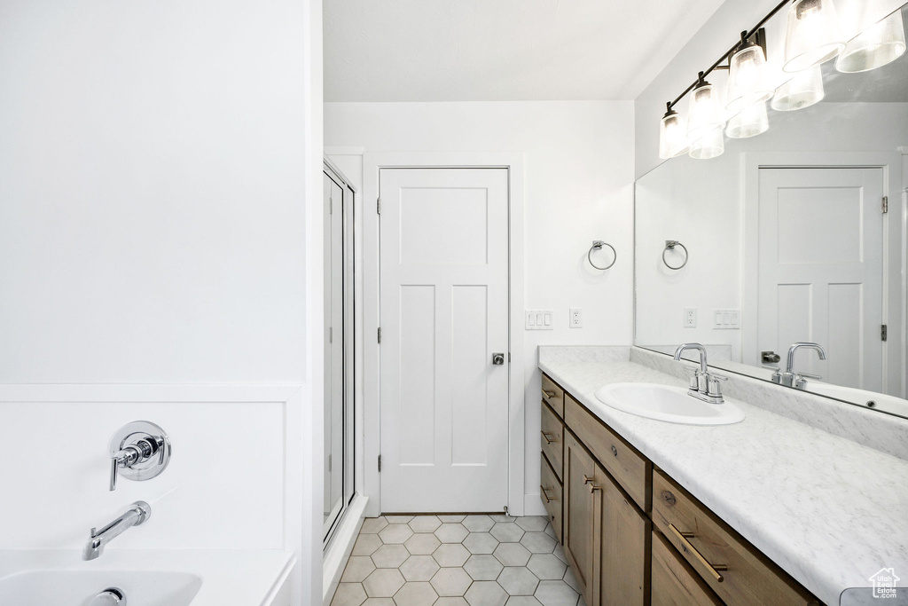 Full bath with tile patterned flooring, vanity, a washtub, and an enclosed shower