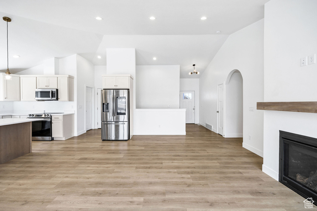Kitchen featuring light countertops, light wood finished floors, appliances with stainless steel finishes, open floor plan, and white cabinets