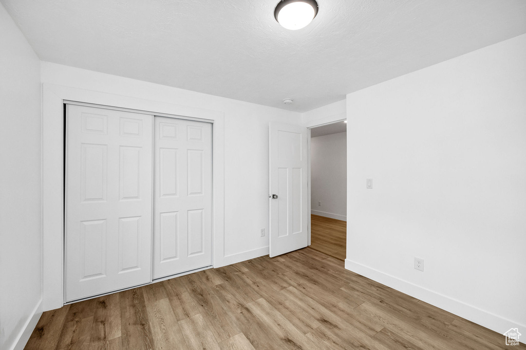 Unfurnished bedroom with baseboards, a closet, and wood finished floors