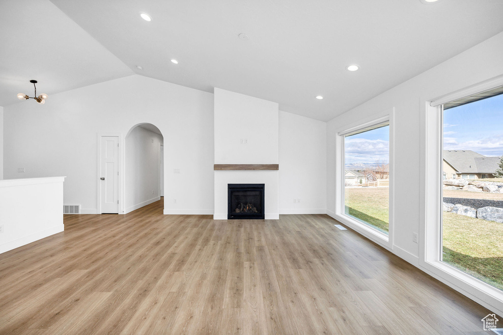 Unfurnished living room with lofted ceiling, recessed lighting, light wood-style floors, visible vents, and a fireplace