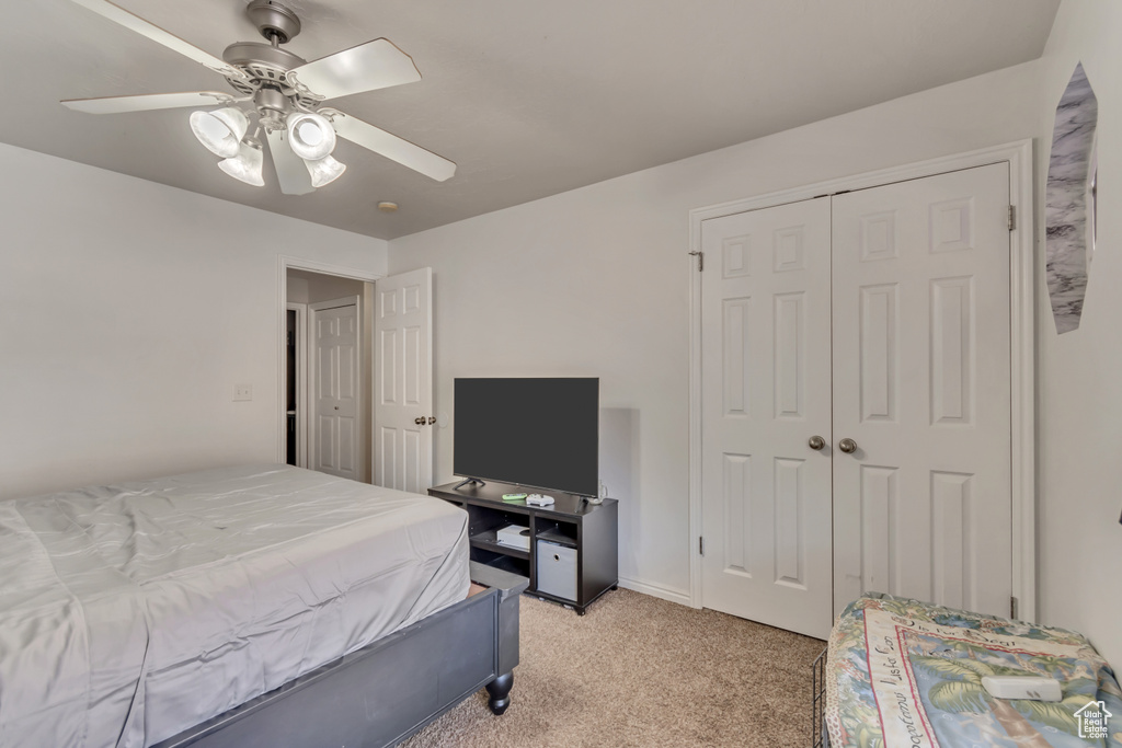 Bedroom with a closet, a ceiling fan, and light colored carpet