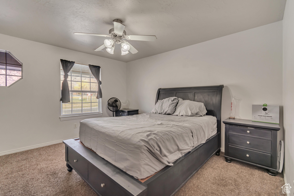 Bedroom featuring light carpet, baseboards, and a ceiling fan