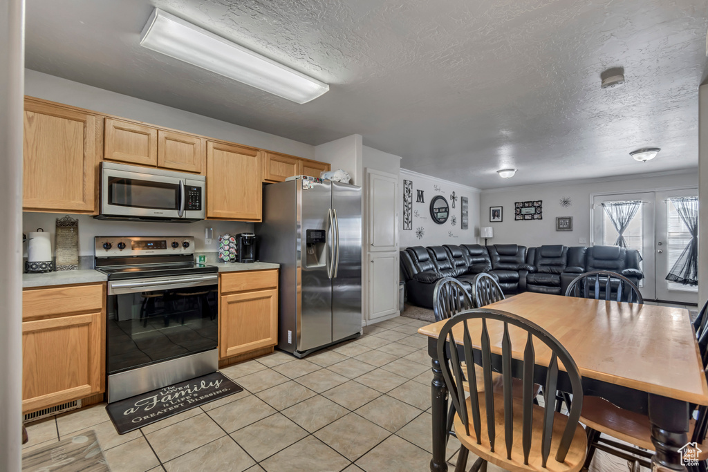 Kitchen featuring open floor plan, light countertops, stainless steel appliances, and light brown cabinetry