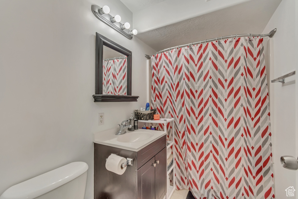 Bathroom with toilet, a shower with shower curtain, and vanity