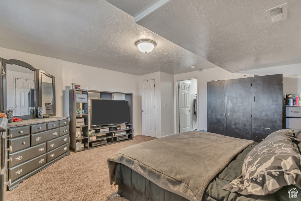 Bedroom with visible vents, carpet floors, and a textured ceiling
