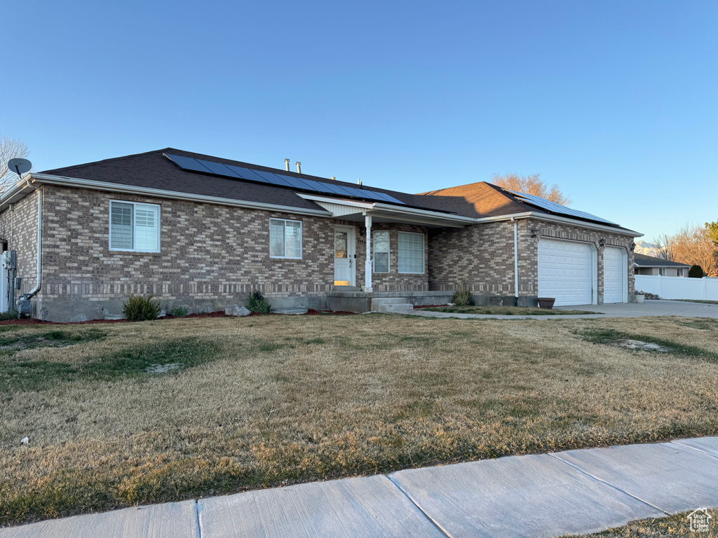 View of front of house featuring fence, an attached garage, concrete driveway, brick siding, and a front lawn