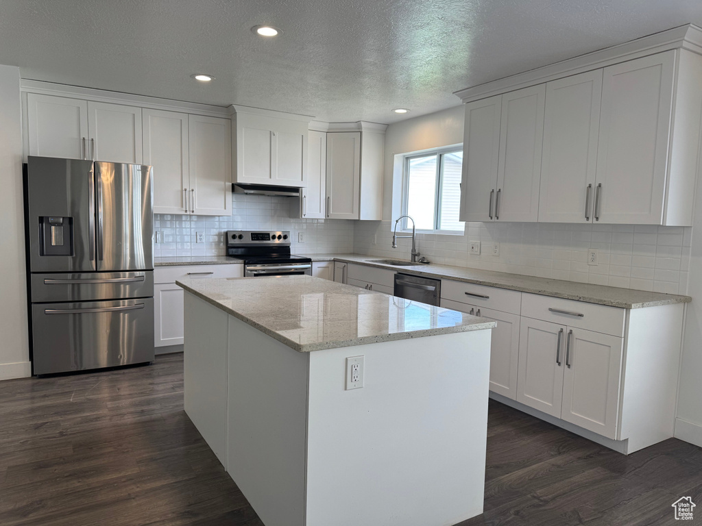 Kitchen featuring dark wood finished floors, white cabinets, a center island, appliances with stainless steel finishes, and a sink