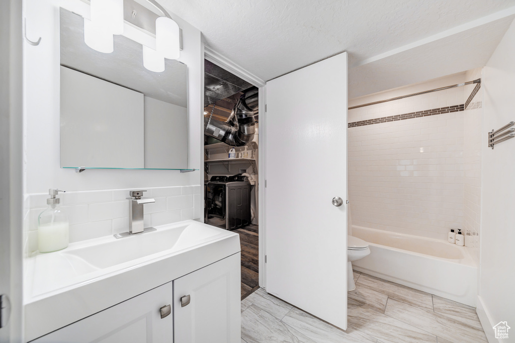 Bathroom with vanity, a spacious closet, toilet, bathtub / shower combination, and decorative backsplash