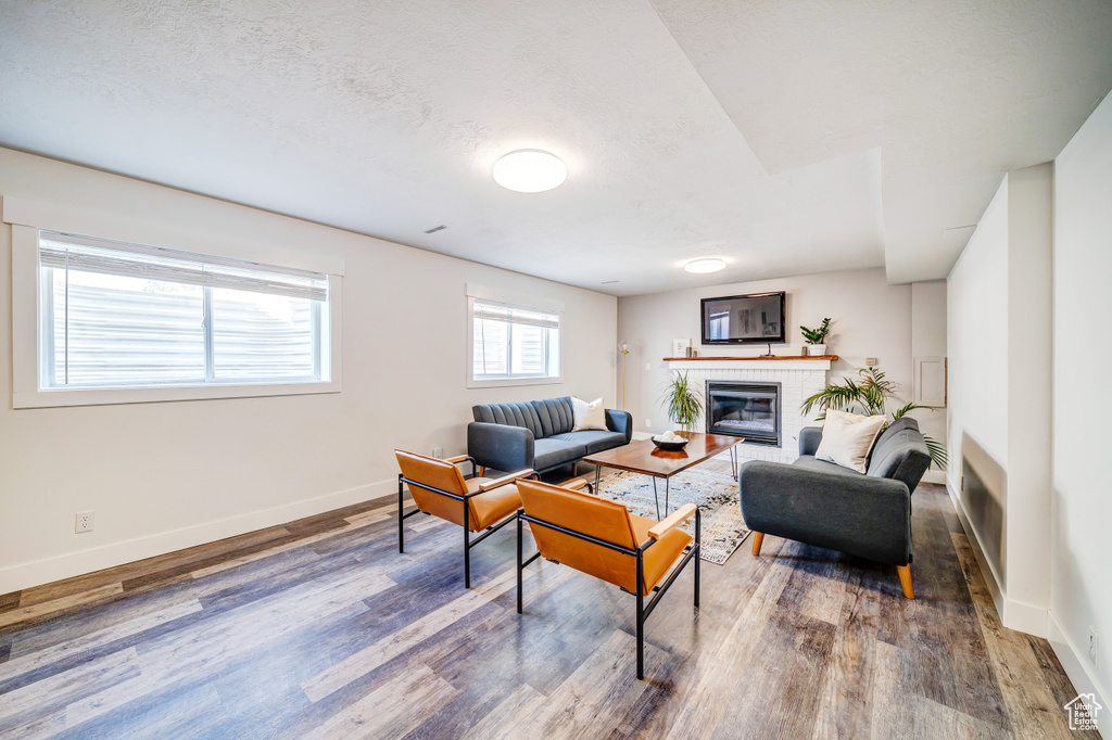 Living area with baseboards, a textured ceiling, a fireplace, and wood finished floors