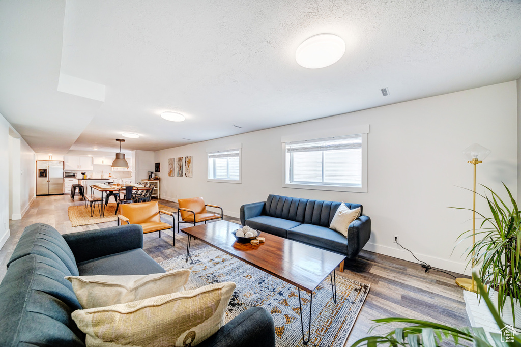 Living area featuring light wood finished floors, baseboards, and a textured ceiling