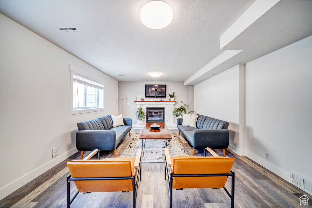 Living room featuring a brick fireplace, wood finished floors, and visible vents