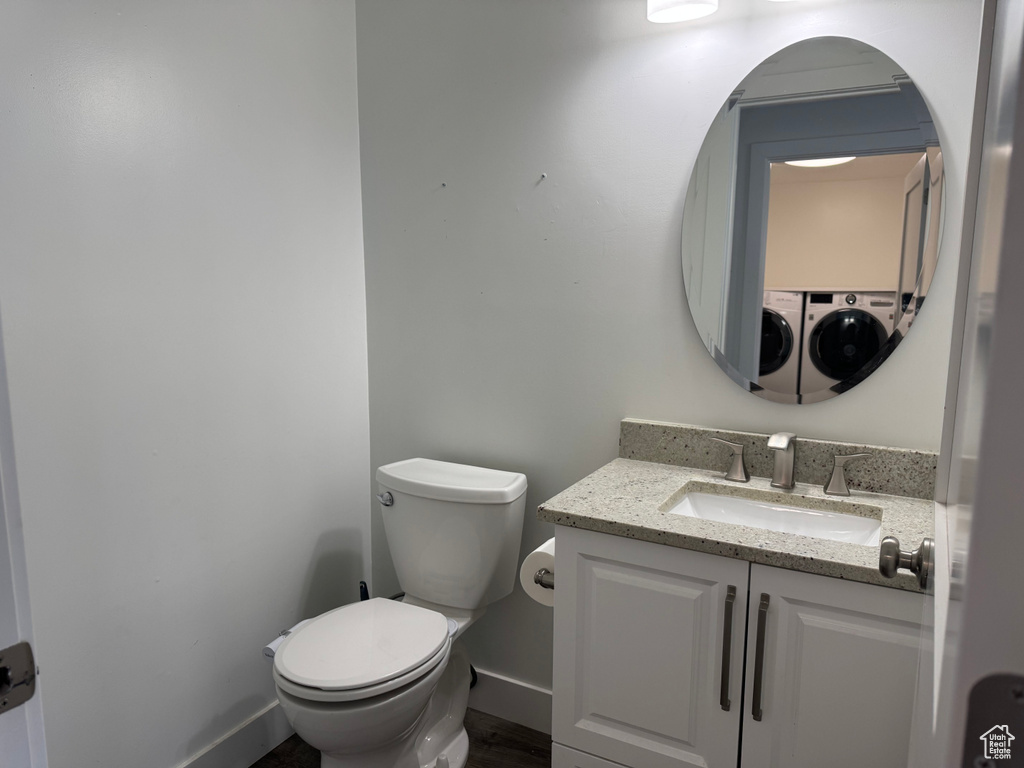 Half bathroom featuring toilet, baseboards, vanity, and wood finished floors