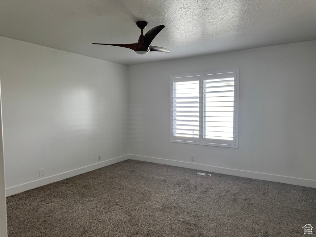 Carpeted spare room featuring baseboards, a ceiling fan, and visible vents