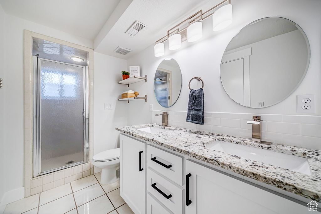 Full bath featuring a stall shower, double vanity, toilet, and a sink