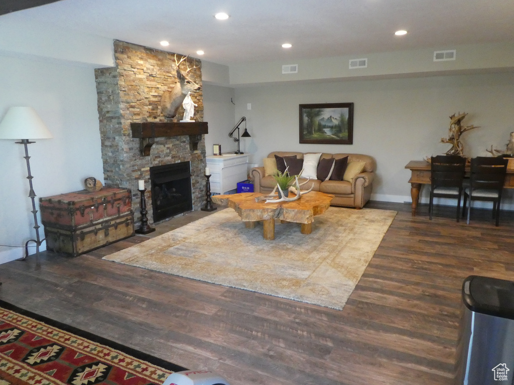 Living area with wood finished floors, a stone fireplace, recessed lighting, and baseboards