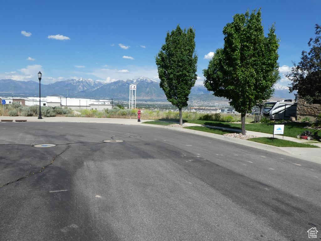 View of asphalt road featuring a mountain view, street lighting, and sidewalks