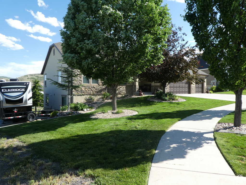 View of front of home featuring a front lawn, stucco siding, stone siding, and a garage