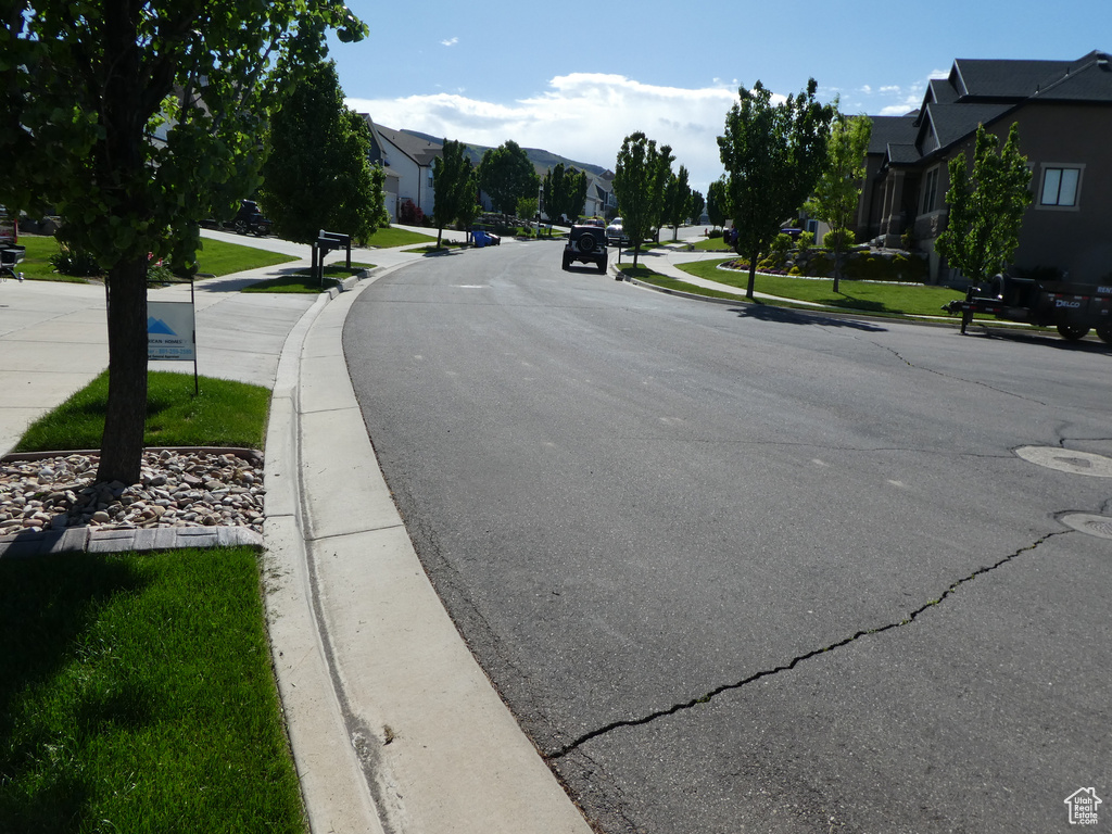 View of asphalt street featuring curbs, a residential view, and sidewalks