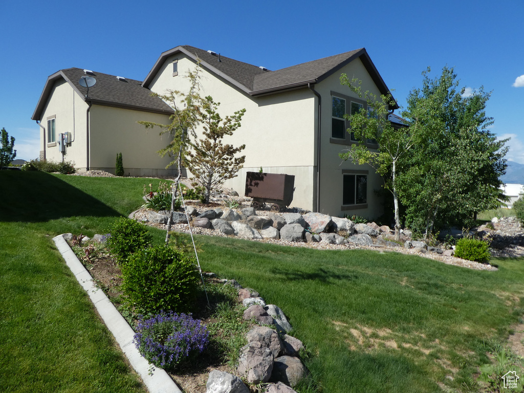 View of side of property featuring stucco siding and a lawn