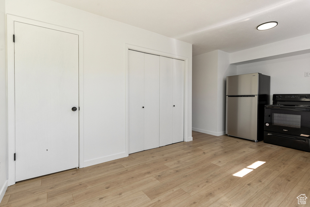 Interior space with freestanding refrigerator, light wood-style flooring, and baseboards