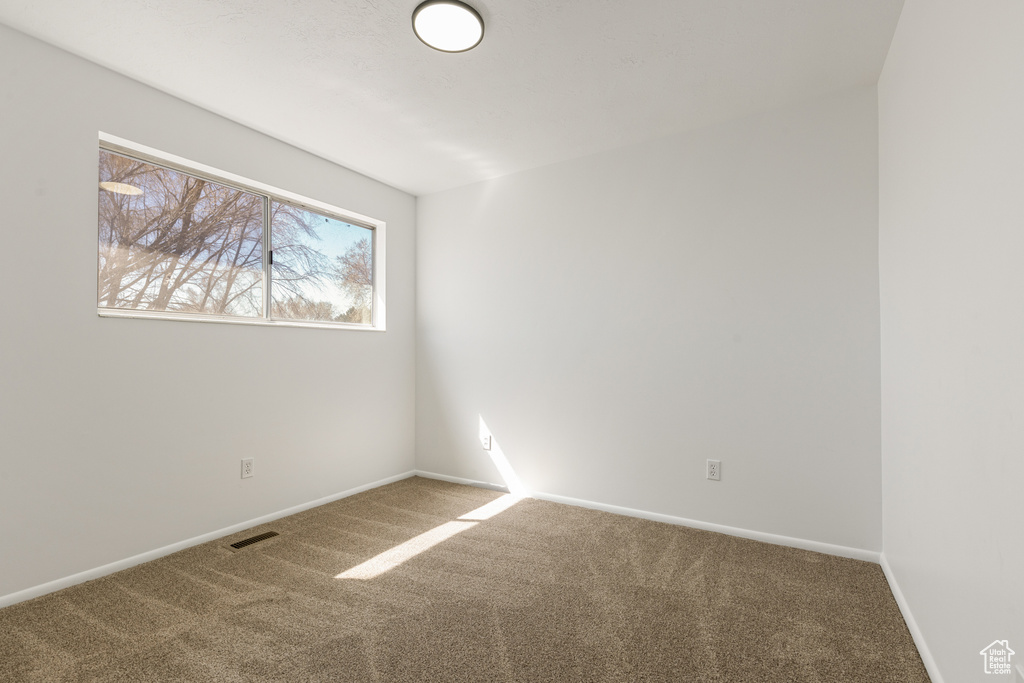 Spare room featuring baseboards, visible vents, and carpet flooring