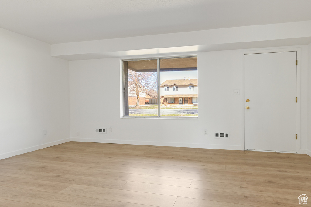 Spare room with baseboards, visible vents, and light wood-style floors