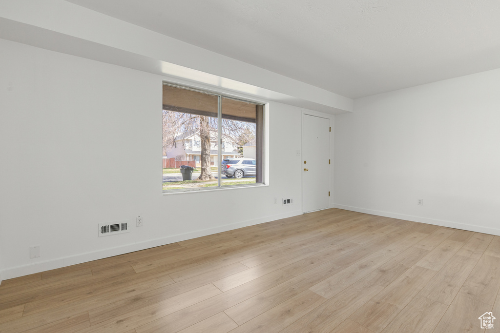 Spare room with light wood finished floors, baseboards, and visible vents