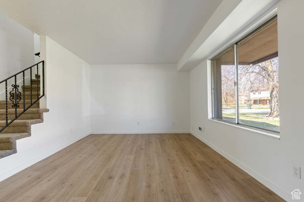 Empty room featuring baseboards, stairs, and wood finished floors