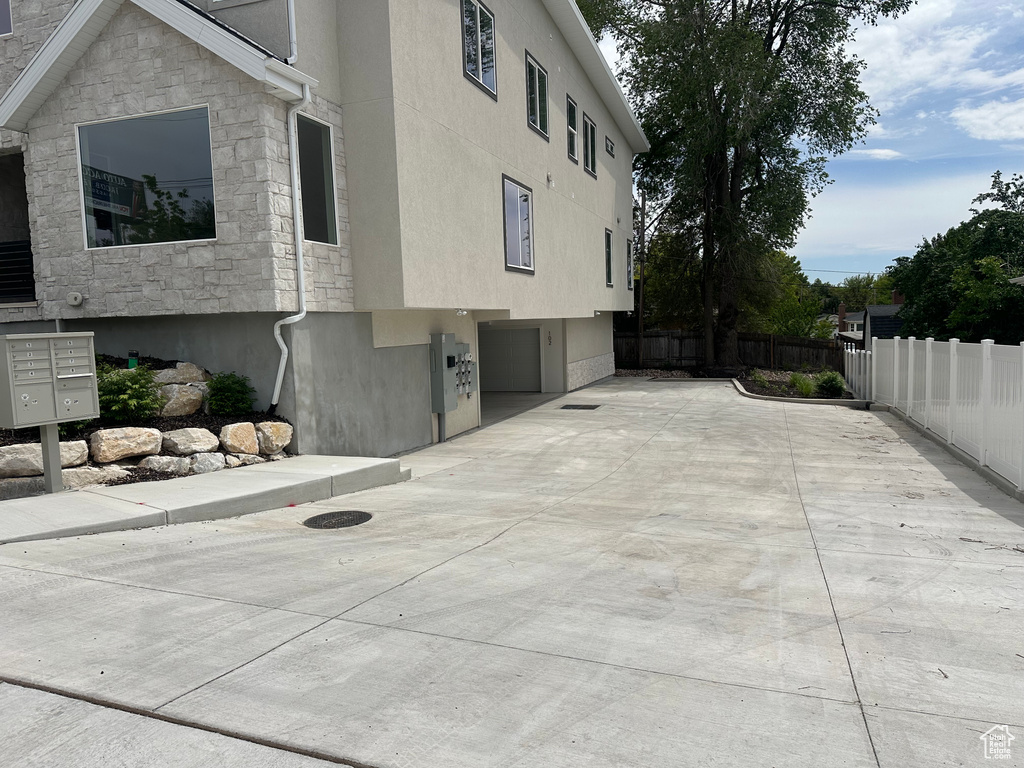 View of property exterior with mail area, stone siding, stucco siding, and an attached garage