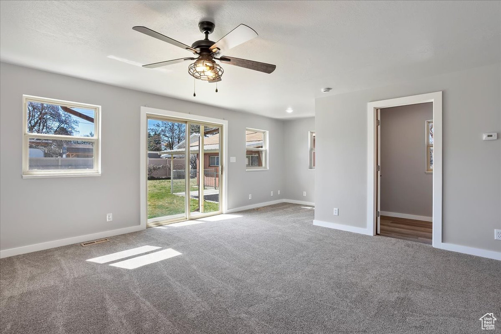 Carpeted empty room featuring baseboards, visible vents, and a ceiling fan