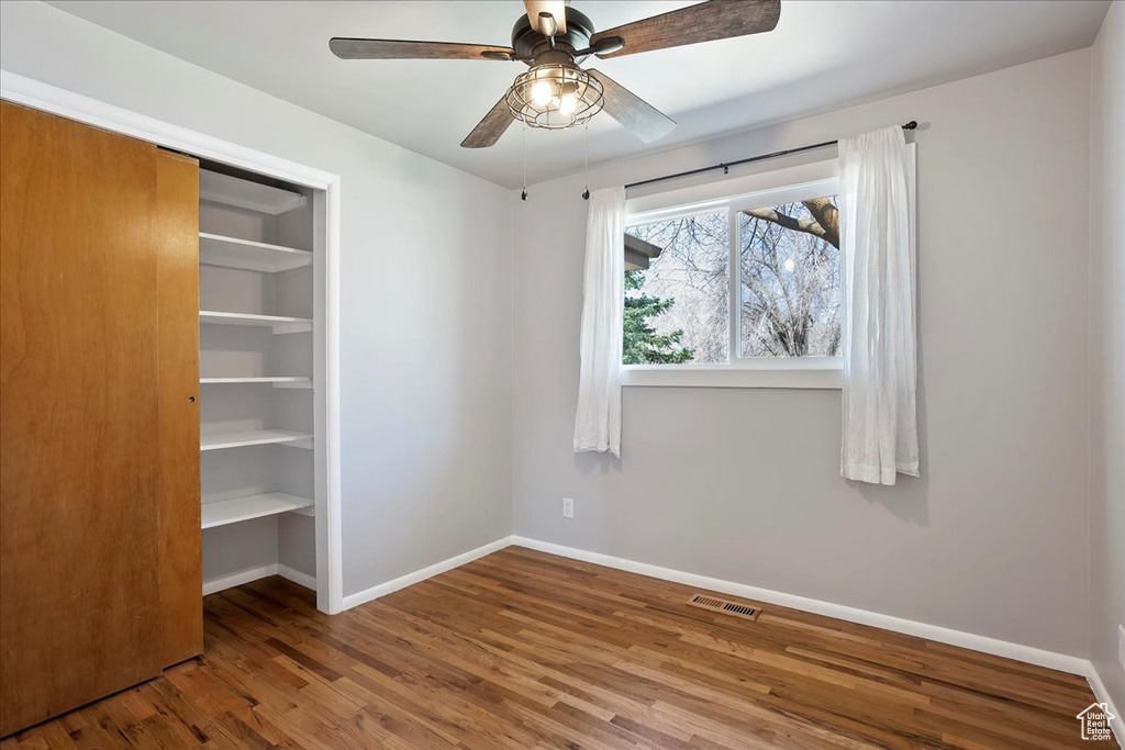 Unfurnished bedroom featuring wood finished floors, a closet, baseboards, and visible vents