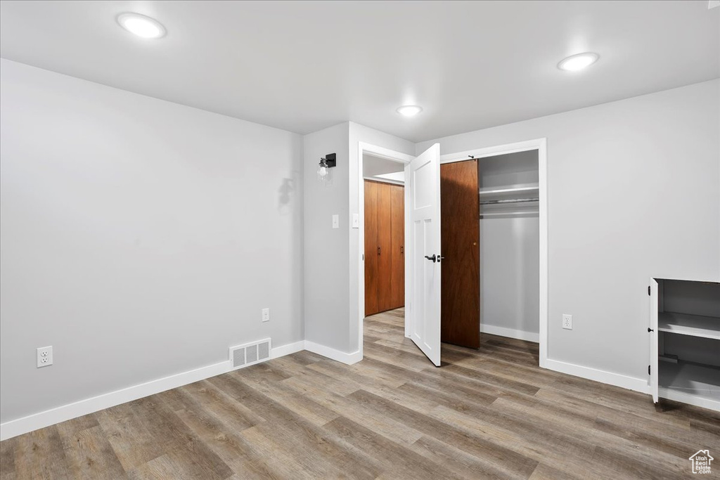 Unfurnished bedroom with wood finished floors, a closet, baseboards, and visible vents