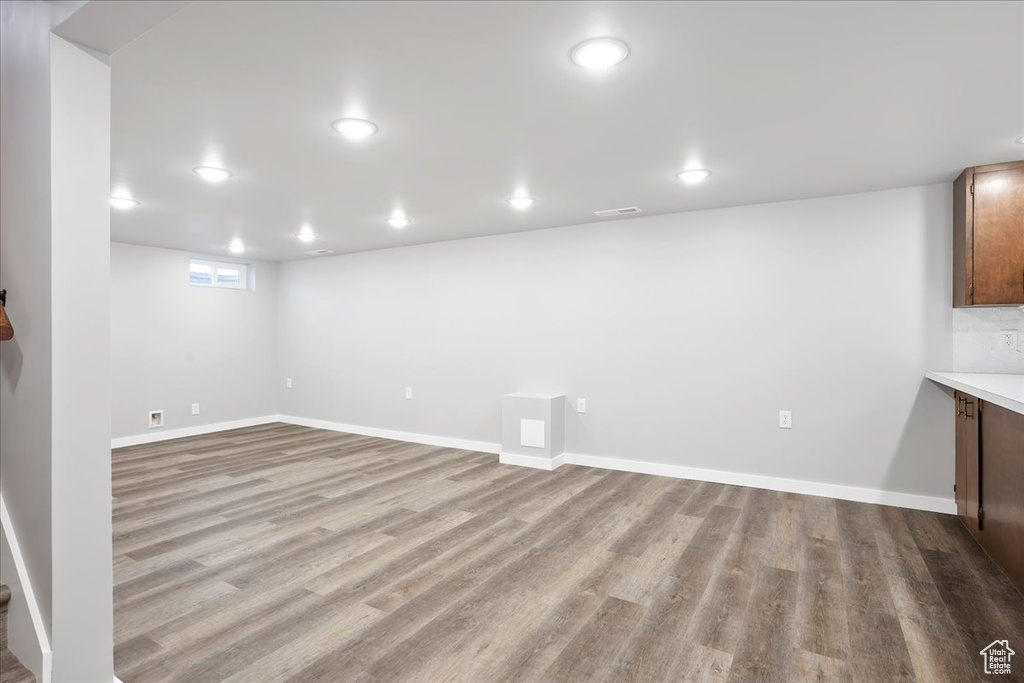 Basement with baseboards, visible vents, and wood finished floors