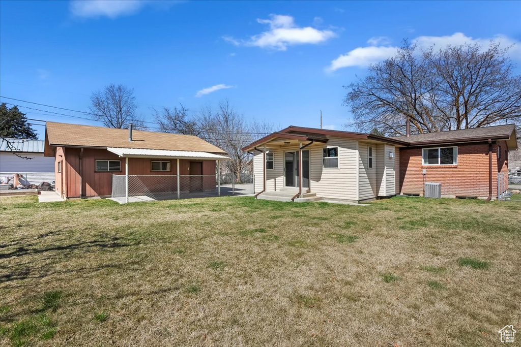 Back of property with fence, entry steps, brick siding, a lawn, and cooling unit