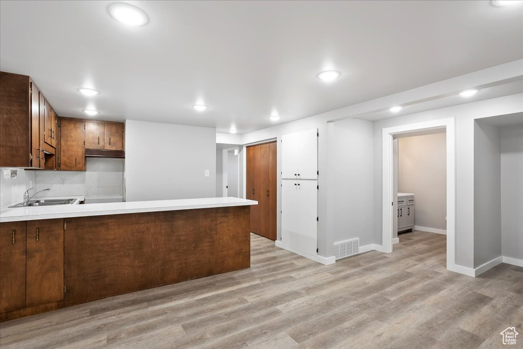 Kitchen featuring light countertops, a sink, visible vents, light wood-style flooring, and a peninsula