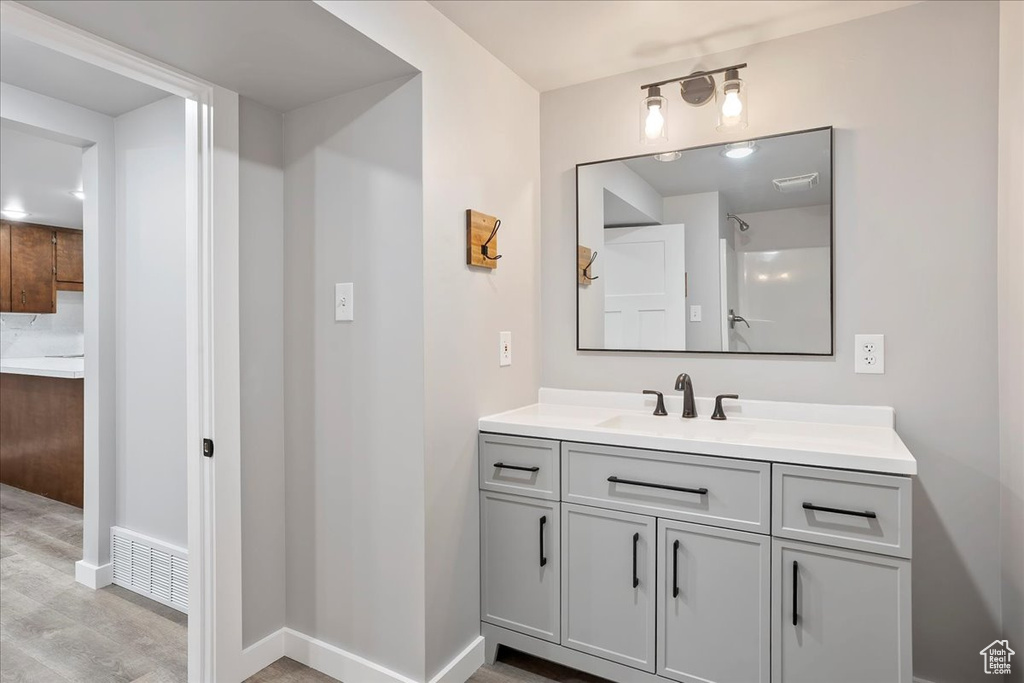 Bathroom with wood finished floors, vanity, baseboards, and visible vents