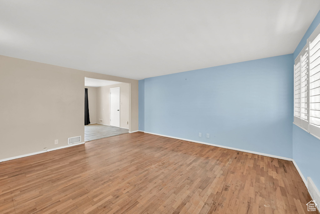 Empty room with baseboards, light wood-style floors, and visible vents