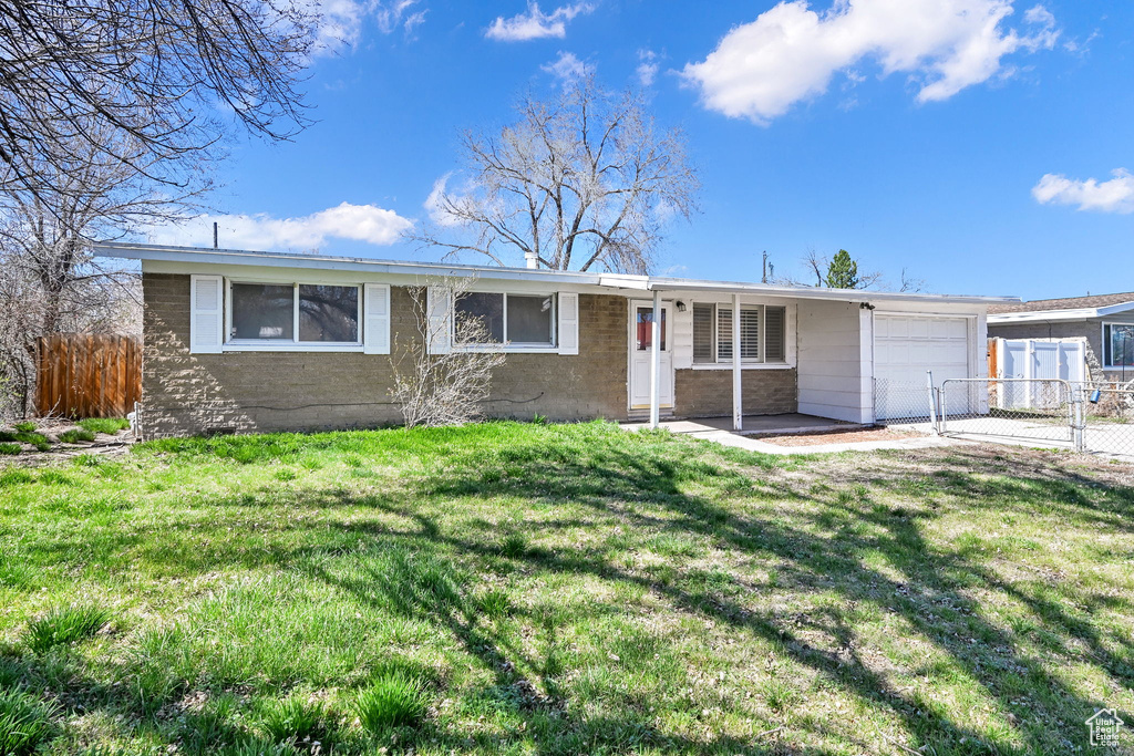 Single story home featuring an attached garage, fence, and a front yard