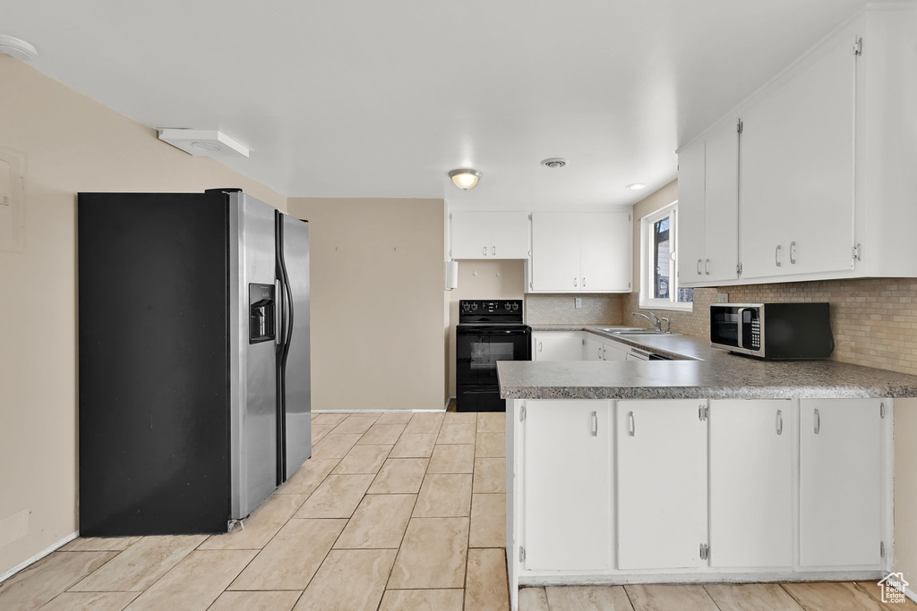 Kitchen featuring a sink, tasteful backsplash, appliances with stainless steel finishes, a peninsula, and white cabinets