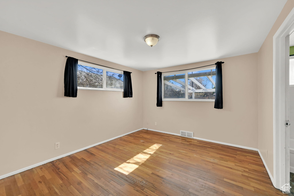 Unfurnished room with hardwood / wood-style flooring, baseboards, and visible vents