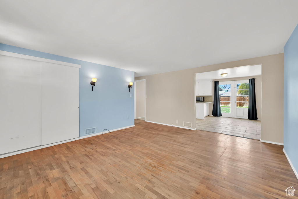 Unfurnished living room with visible vents, baseboards, and light wood-type flooring