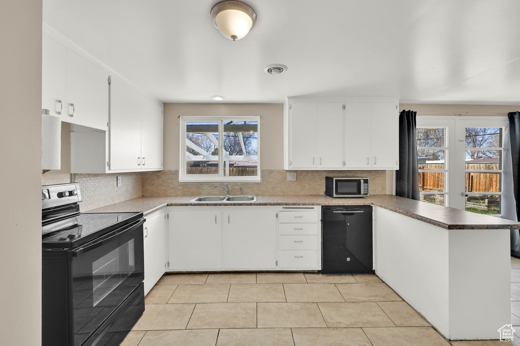 Kitchen featuring decorative backsplash, a sink, visible vents, a peninsula, and black appliances