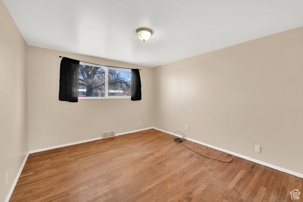 Spare room with wood finished floors, baseboards, and visible vents
