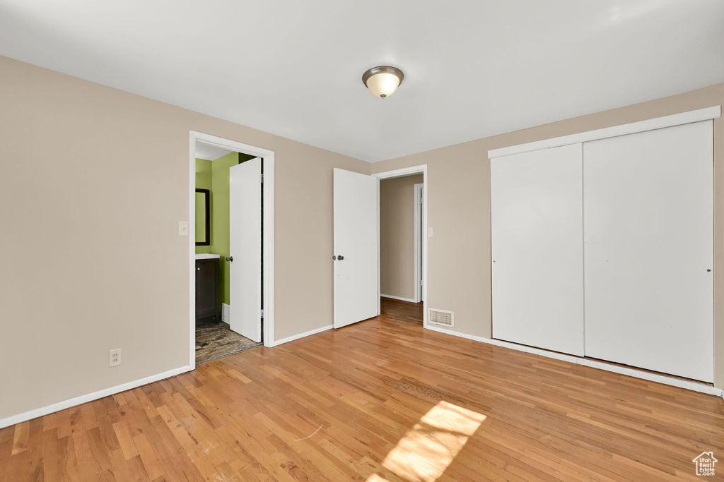 Unfurnished bedroom with baseboards, a closet, visible vents, and light wood-style floors