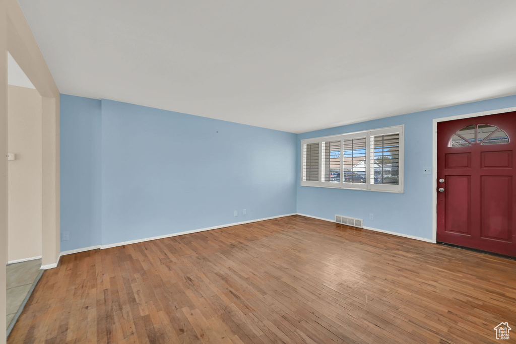 Foyer entrance with hardwood / wood-style flooring, baseboards, and visible vents