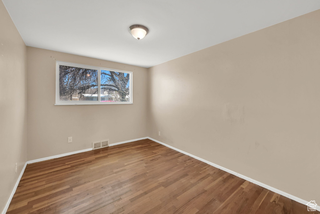 Spare room with baseboards, visible vents, and wood finished floors