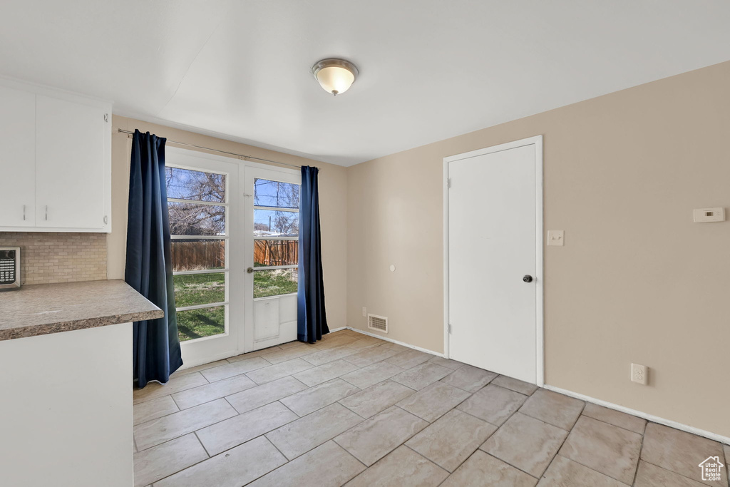 Unfurnished dining area with baseboards, visible vents, and light tile patterned floors